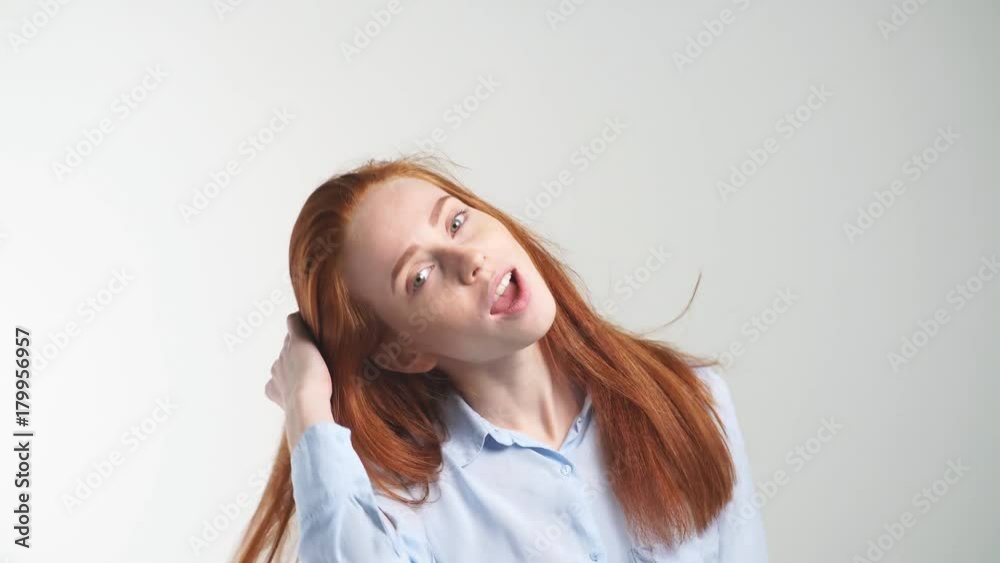 Cheerful young redhead girl dancing and looking at camera on white background. Cheerful young redhead girl dancing and looking at camera on white background.