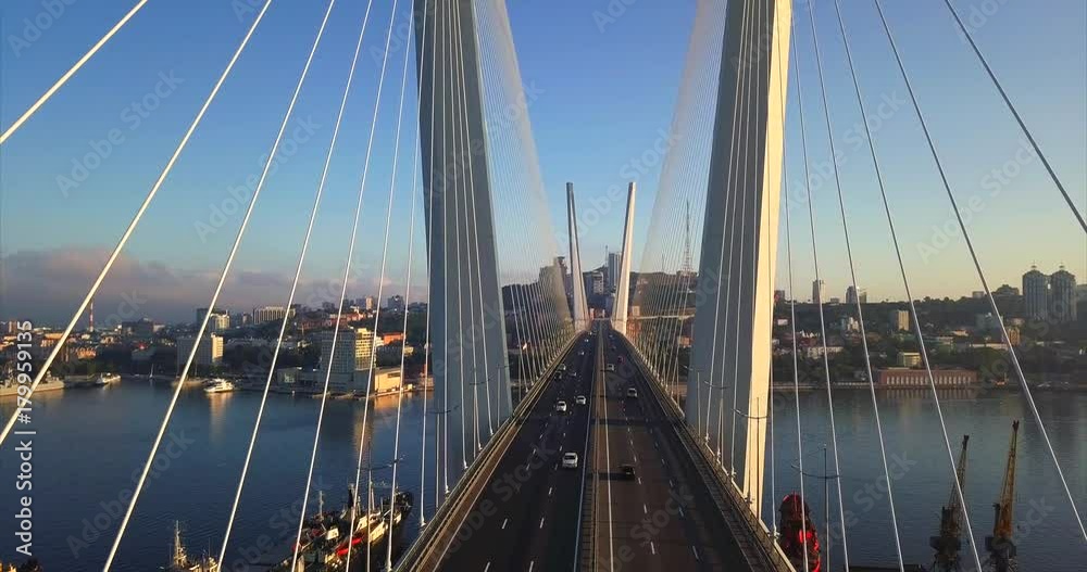 Descending above the road between stay cables of Zolotoy Bridge (Golden Bridge, cable-stayed bridge across Zolotoy Rog harbour built in 2012). Aerial view of cars driving across it. Vladivostok,Russia Descending above the road between stay cables of Zolotoy Bridge (Golden Bridge, cable-stayed bridge across Zolotoy Rog harbour built in 2012). Aerial view of cars driving across it. Vladivostok,Russia
