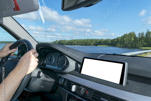 Male hands holding car steering wheel. Hands on steering wheel of a car driving near the palm. Man driving a car inside cabin. Multimedia system isolated white blank screen. Copy space