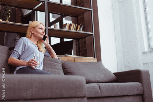 woman drinking water and talking on smartphone