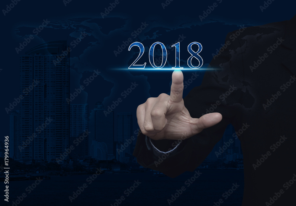 Businessman pressing 2018 text over world map and modern city tower, Happy new year concept, Elements of this image furnished by NASA Businessman pressing 2018 text over world map and modern city tower, Happy new year concept, Elements of this image furnished by NASA