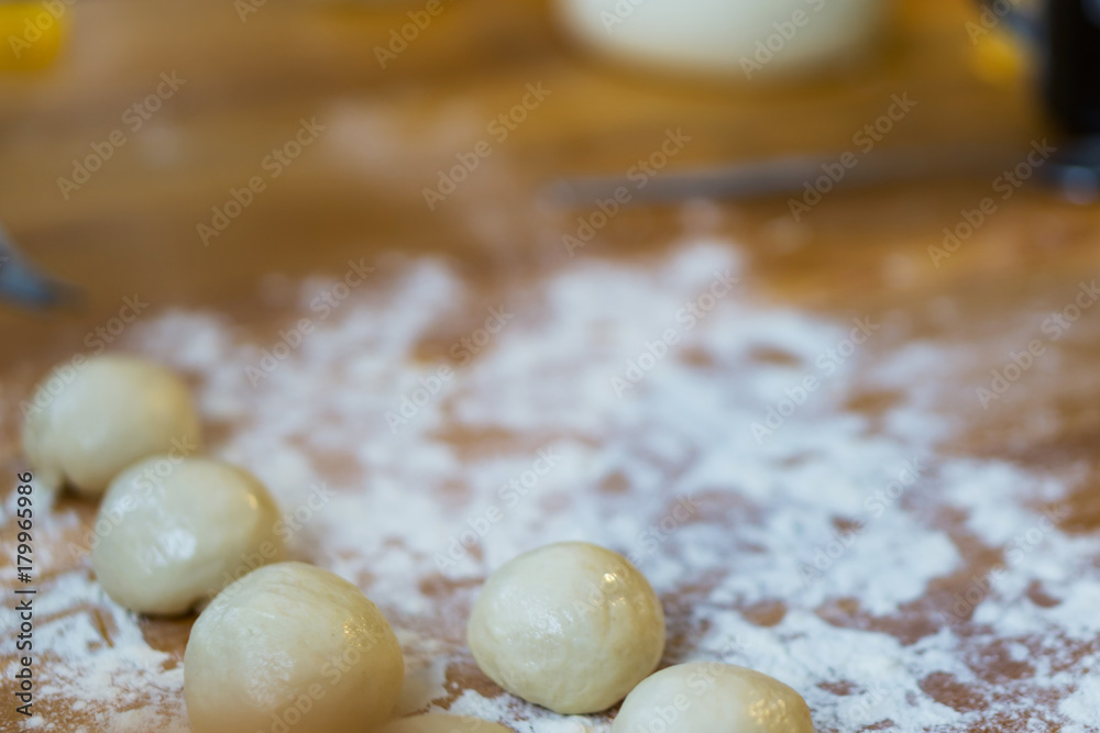 Closeup of small balls ready dough on floured kitchen table. Defokus in the background. Closeup of small balls ready dough on floured kitchen table. Defokus in the background.