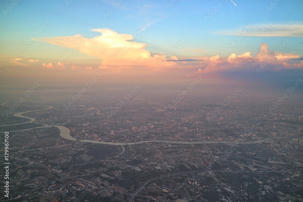 Aerial view of Bangkok, Thailand, with building in big city, evening sky and colorful cloud. View from airplane's window. Soft focus with low key.