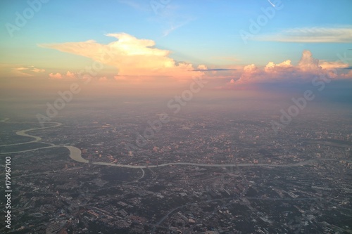 Aerial view of Bangkok, Thailand, with building in big city, evening sky and colorful cloud. View from airplane's window. Soft focus with low key. © Aungsumol