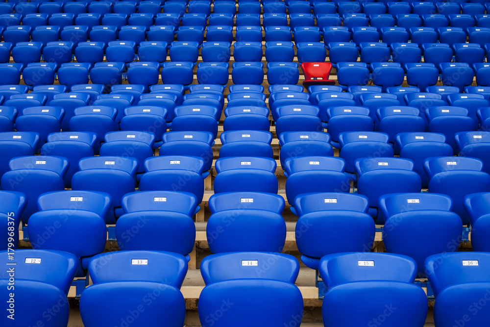 Naklejka premium Czerwony fotel w rzędzie niebieskich foteli. Być innym. Bądź wyjątkowy.