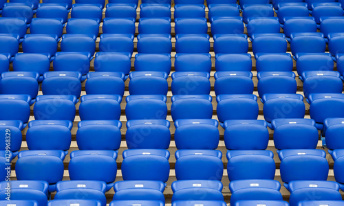 Rows of blue plastic armchairs on a tribune of stadium.