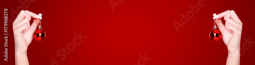 Red Christmas banner with hands and Christmas balls. New Year background. Copy space.