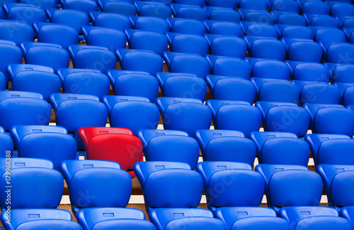 Red armchair on a background of blue armchairs. Be different. Be special. © Dymov