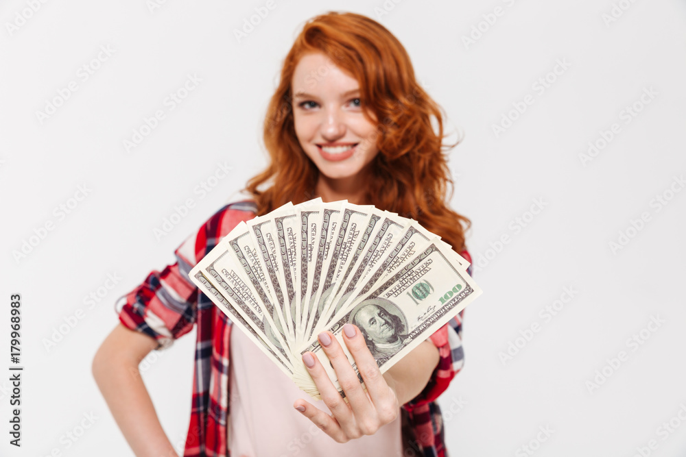 Cheerful pretty young redhead lady holding money. Cheerful pretty young redhead lady holding money.