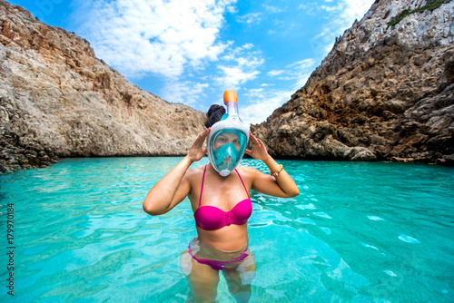 Portrait of attractive young woman posing with snorkeling mask, smiling and enjoying vacation
