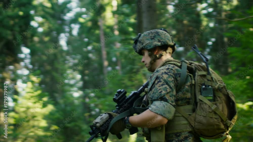 Fully Equipped Soldiers Wearing Camouflage Uniform Attacking Enemy, Rifles in Firing Position. Military Operation in Action, Squad Running in Formation Through Dense Forest. Side View Long Shot. Fully Equipped Soldiers Wearing Camouflage Uniform Attacking Enemy, Rifles in Firing Position. Military Operation in Action, Squad Running in Formation Through Dense Forest. Side View Long Shot.