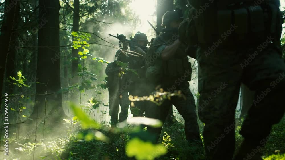 Squad of Five Fully Equipped Soldiers in Camouflage on a Reconnaissance Military Mission, Rifles Ready to Shoot. They're Moving in Formation Through Dense Sunny Forest.