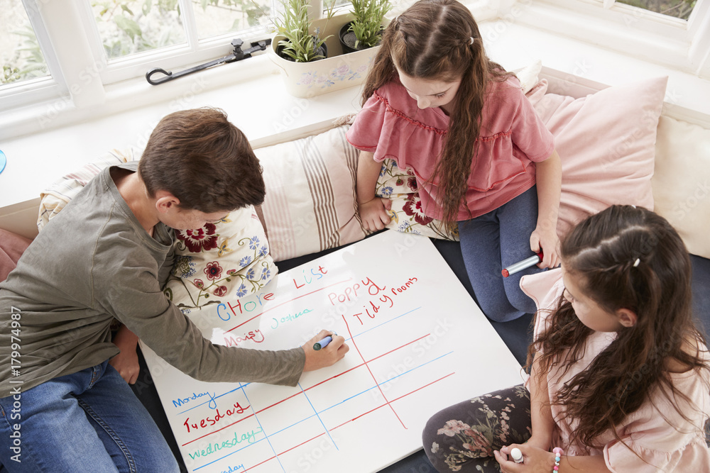 Children Making List Of Chores On Whiteboard At Home Children Making List Of Chores On Whiteboard At Home