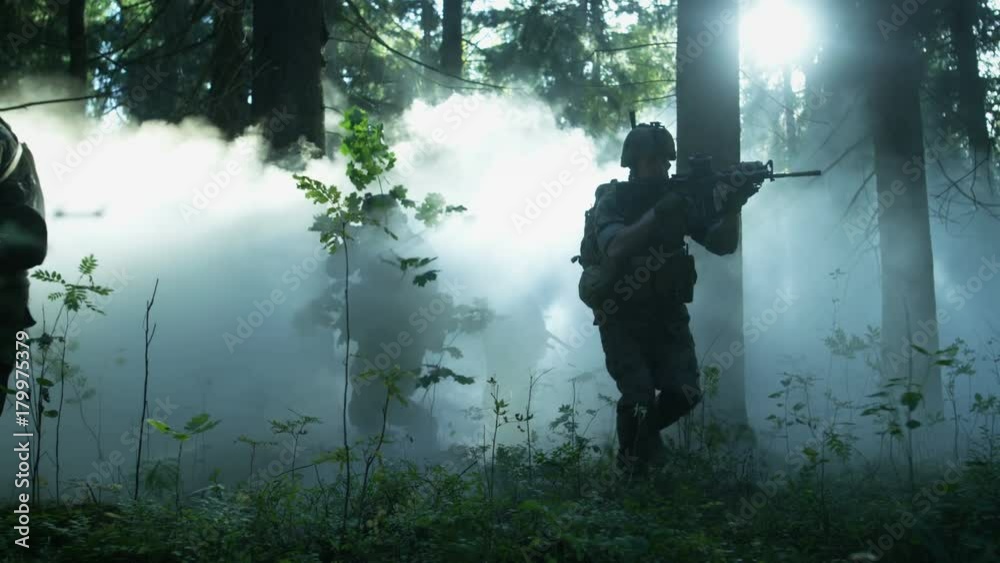 Fully Equipped Soldiers Wearing Camouflage Uniform Attacking Enemy, Rifles Ready to Shoot. Military Operation in Action, Squad Running in Formation Through Dense Smokey Forest. Fully Equipped Soldiers Wearing Camouflage Uniform Attacking Enemy, Rifles Ready to Shoot. Military Operation in Action, Squad Running in Formation Through Dense Smokey Forest.