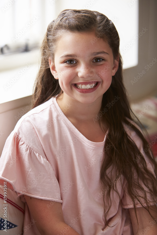 Portrait Of Smiling Young Girl Sitting On Window Seat At Home Portrait Of Smiling Young Girl Sitting On Window Seat At Home