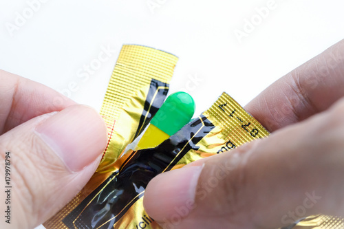 Obraz na plátne Hands tearing blister pack of green and yellow capsule, medical pill