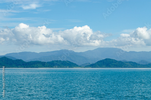 Horizontal of Seascape including Forest Mountain, Blue Sky and Wave of Water Foam in Ocean. © ruzella