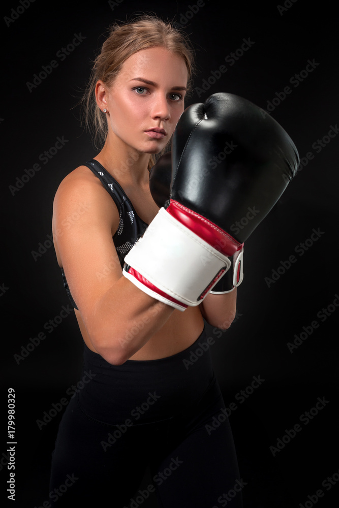 Beautiful female athlete in boxing gloves, in the studio on a black background. Focus on the glove