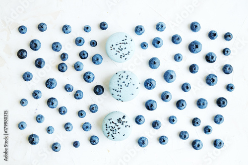 Freshly picked blueberries on white, fresh sweet macaroons. Flat lay.