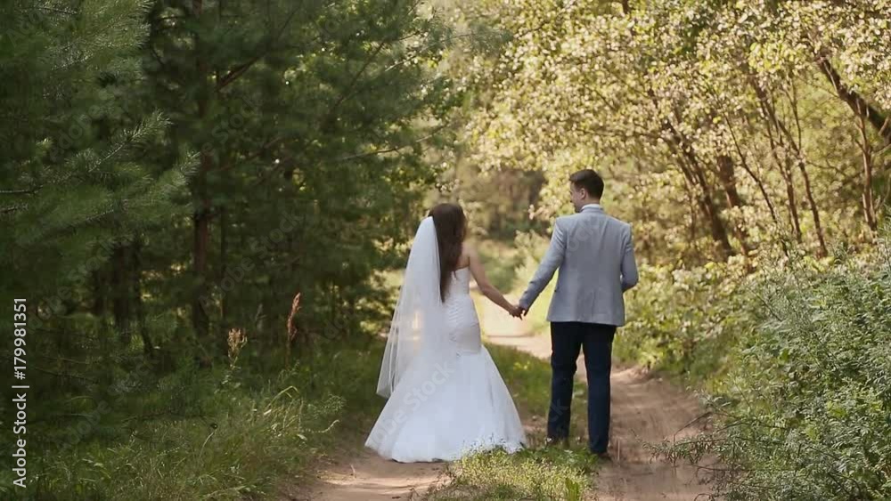 Bride in white dress and groom in the forest. They walk together holding hands. Happy together. Wedding day. Bride in white dress and groom in the forest. They walk together holding hands. Happy together. Wedding day.