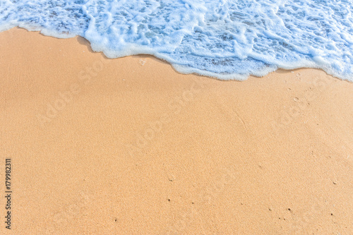 Soft wave with blue ocean on sandy beach.