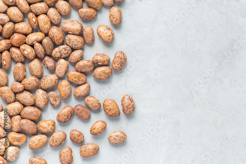 Fotografie Uncooked dry pinto beans on a gray concrete background, top view, copy space