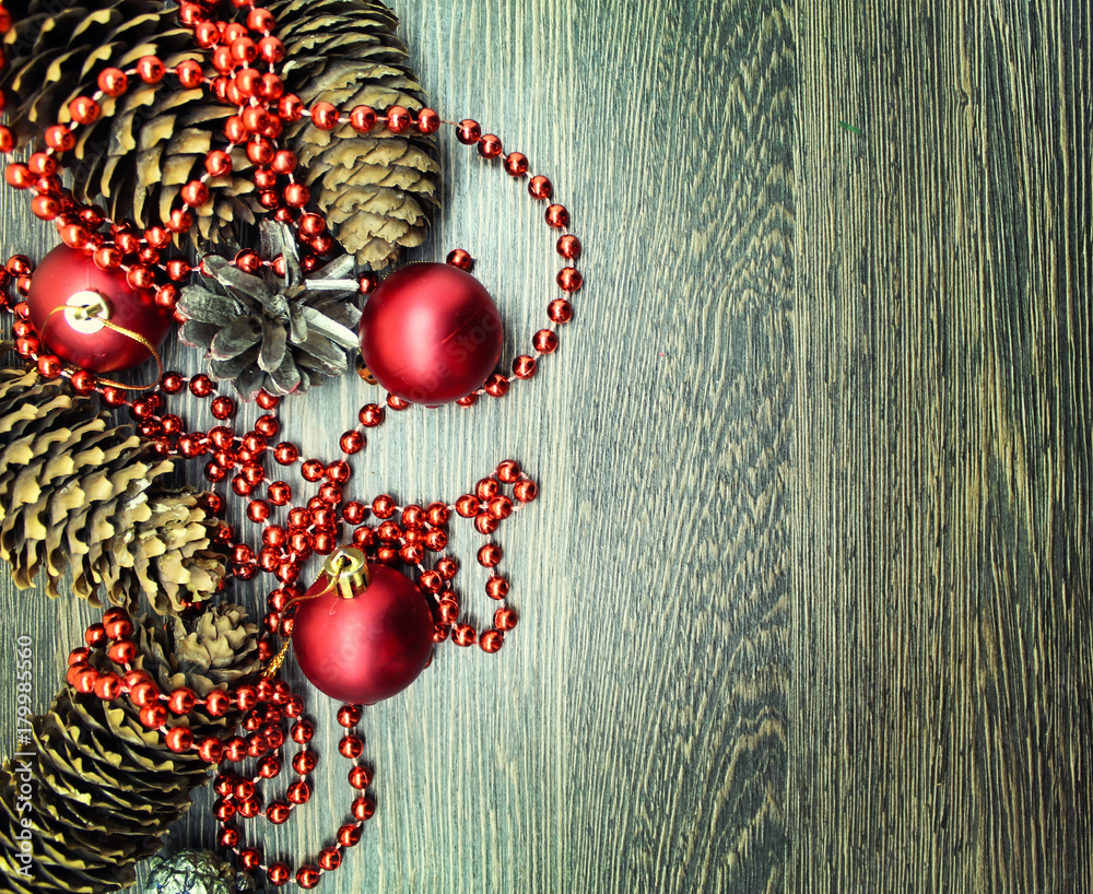 Naklejka premium Christmas balls, cones and ornaments on wooden background. 