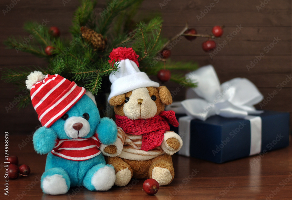A small  toy dog fnd teddy bear in a knitted cap, gift boxes, nuts and Christmas spruce branches. Christmas and New Year card. Still life.