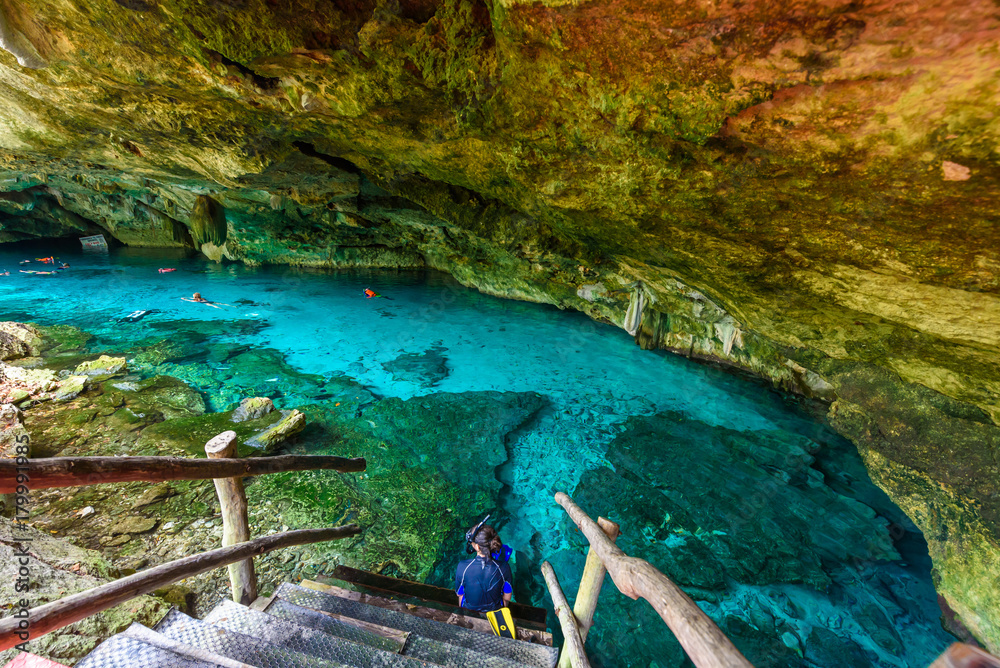Cenote Dos Ojos in Quintana Roo, Mexico. People swimming and snorkeling in clear blue water. This cenote is located close to Tulum in Yucatan peninsula, Mexico.