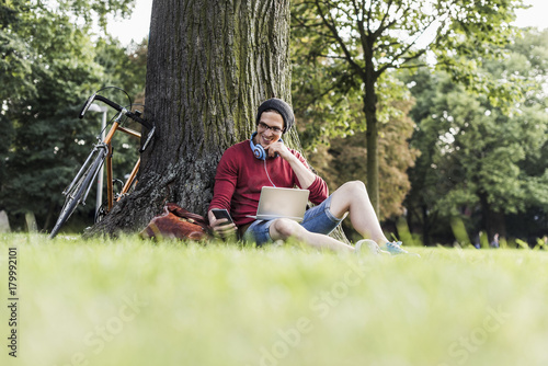 Man using laptop and cell phone in park
