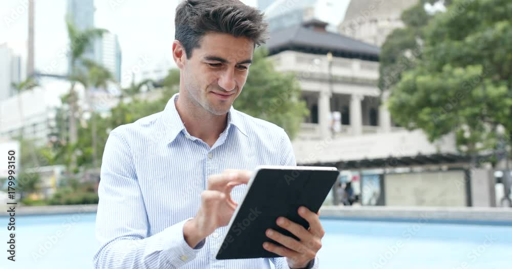Hispanic man use of digital tablet computer in city