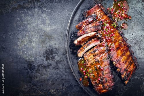 Fotografia Barbecue pork spare ribs with fruit relish as top view on an old rustic board wi