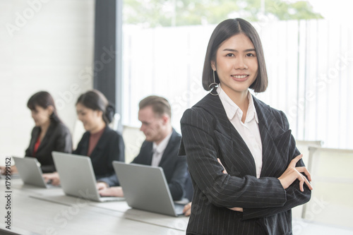Asian Woman standing in front of her team with smiling, Female with her team working in the office, . Woman Leader Concept.