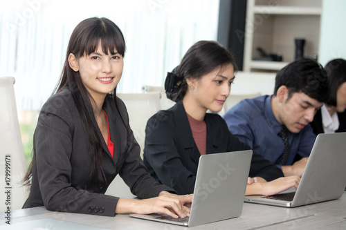 Asian Woman sitting in front of her team with smiling, Female with her team working in the office, Woman Leader Concept.