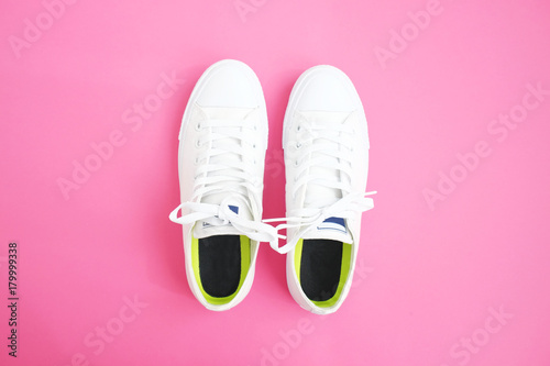 Flat lay of female sneakers on a pink background. Place for your design, text