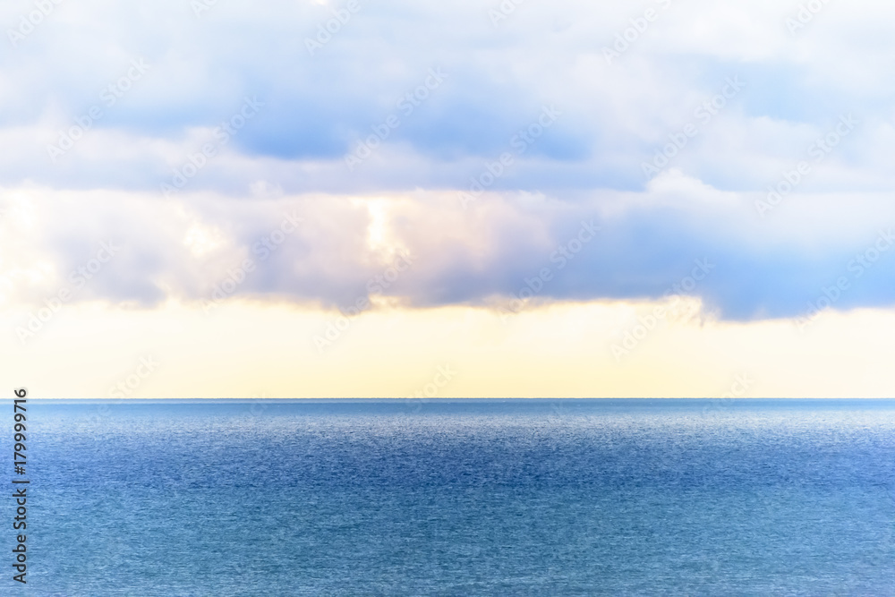 Stylized abstract landscape seascape sunset long exposure with clouds under different shades of blue, orange, yellow and red.