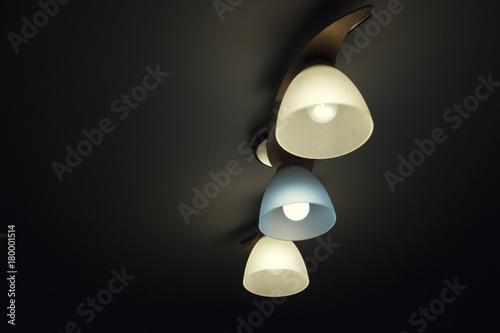 Chandelier with three light bulbs, warm and cold light on a dark background © Valentine