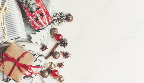 christmas flat lay. wrapped presents with ornaments car toy and pine cones anise on rustic white wooden background top view, space for text. stylish gifts. seasonal greetings. happy holidays