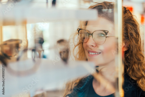 Happy girl deciding to buy new glasses. photo