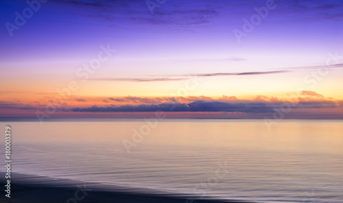 Stylized abstract landscape seascape sunset long exposure with clouds under different shades of blue  orange  yellow and red.