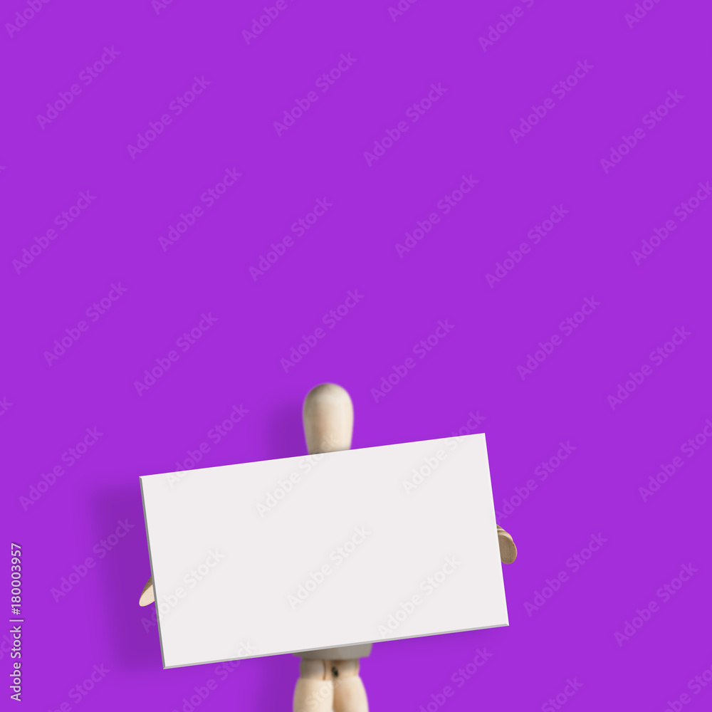 White empty board in front of wooden mannequin on purple background White empty board in front of wooden mannequin on purple background