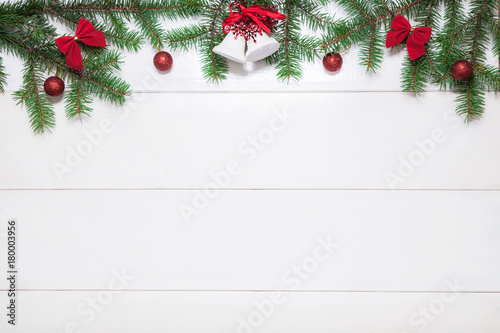 Christmas background with fir branches, balls, bells  on white wooden surface. Backdrop with copy space.