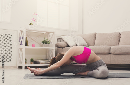 Woman training yoga in seated head to knee pose.