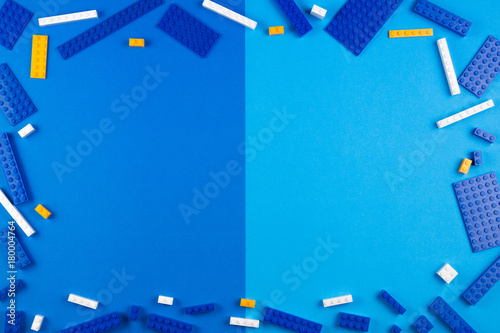 Toys background. Blue, white and yellow plastic construction blocks on blue background photo