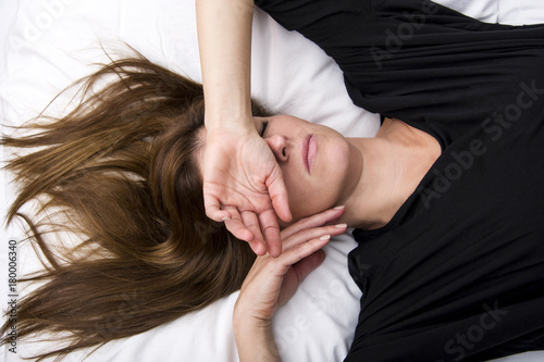 Depressed young woman is lying in her bed, covering her eyes.Sorrow concept.