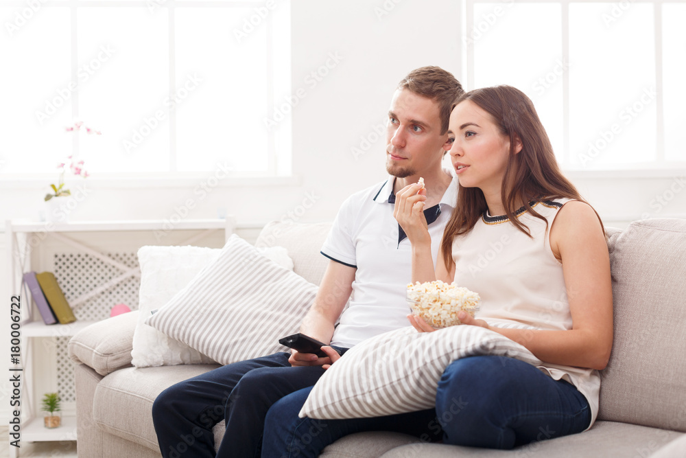 Smiling young couple watching TV at home
