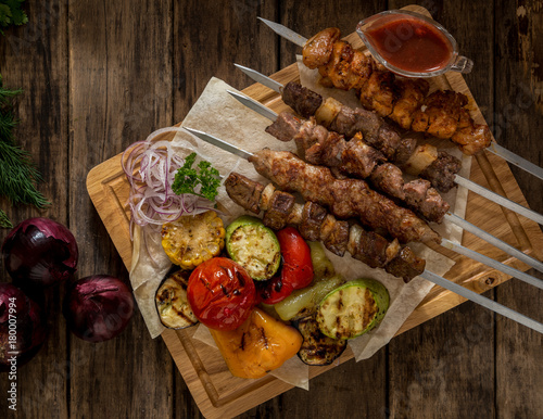 grilled meat with vegetables on skewers on wooden boards, top view