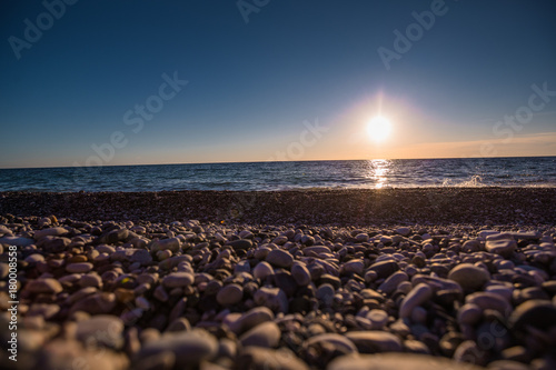 stone beach on blue sky background with sun © Nikita Shevchenko