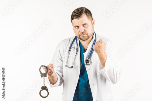A doctor in a white lab coat with a stethoscope holds the handcuffs in his hand. On a white background