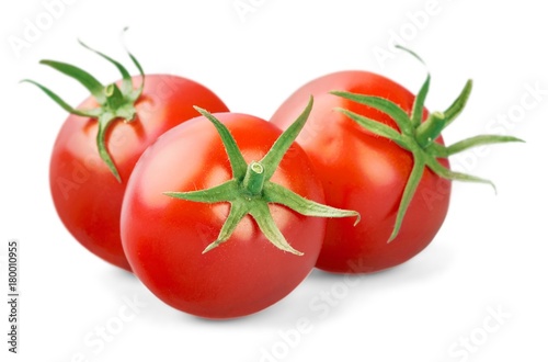 three fresh tomatoes with green leaves isolated on white